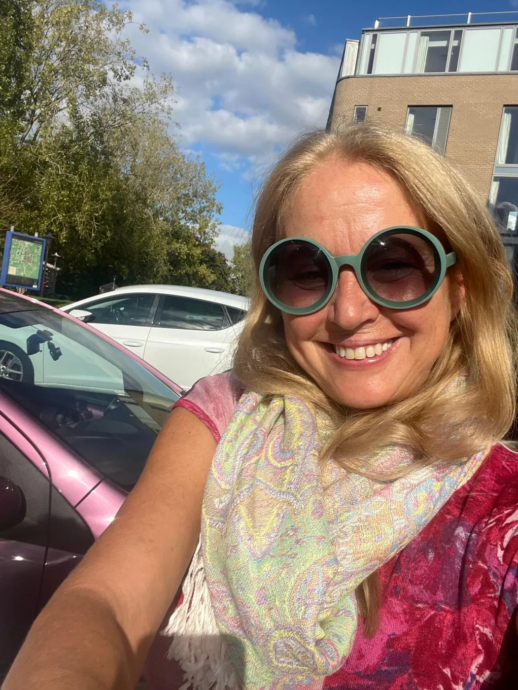 Die Wunderfrau mit farbigem Schal und Sonnenbrille draußen.